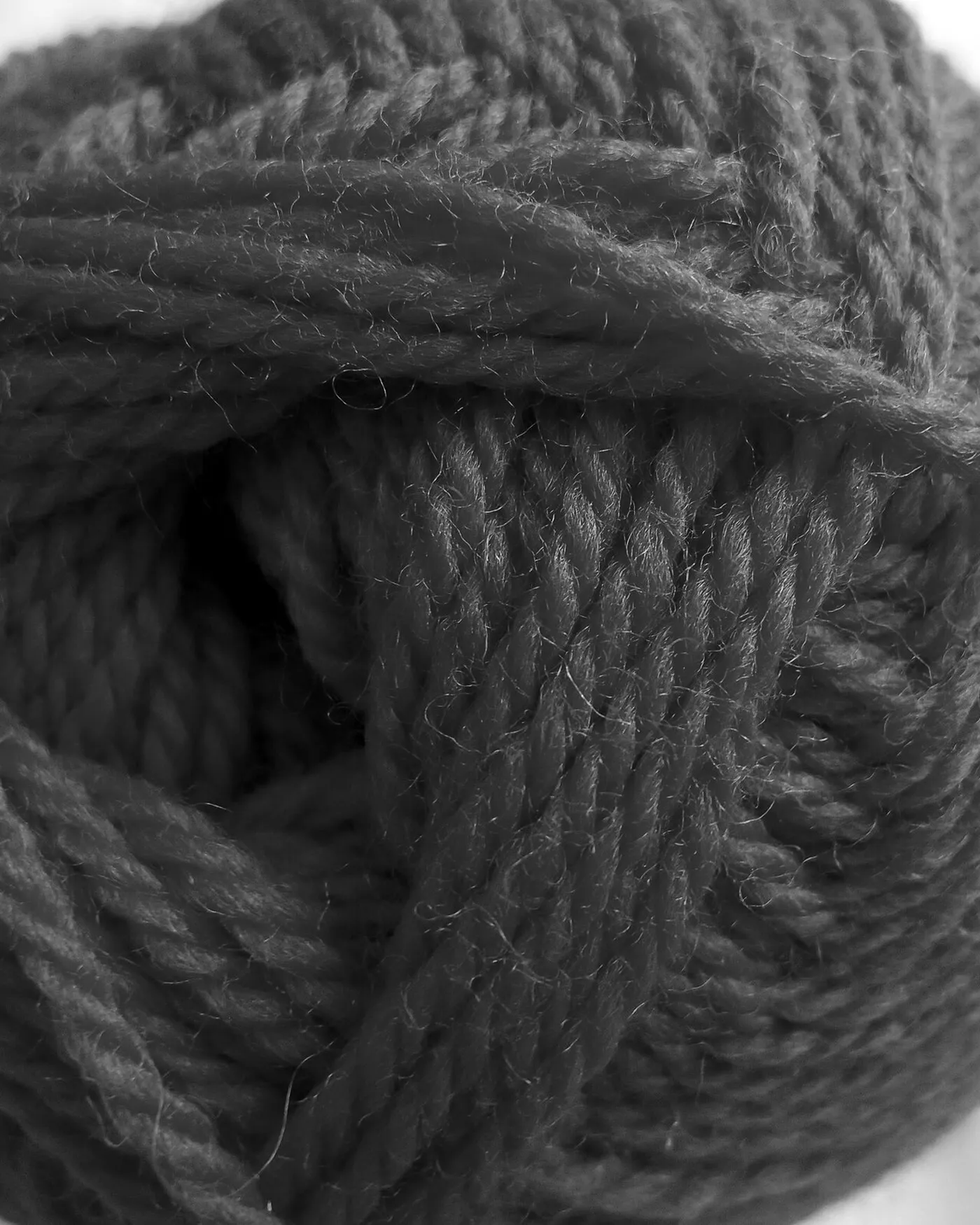 A ball of woollen yarn, wound tight, on a plain ground.